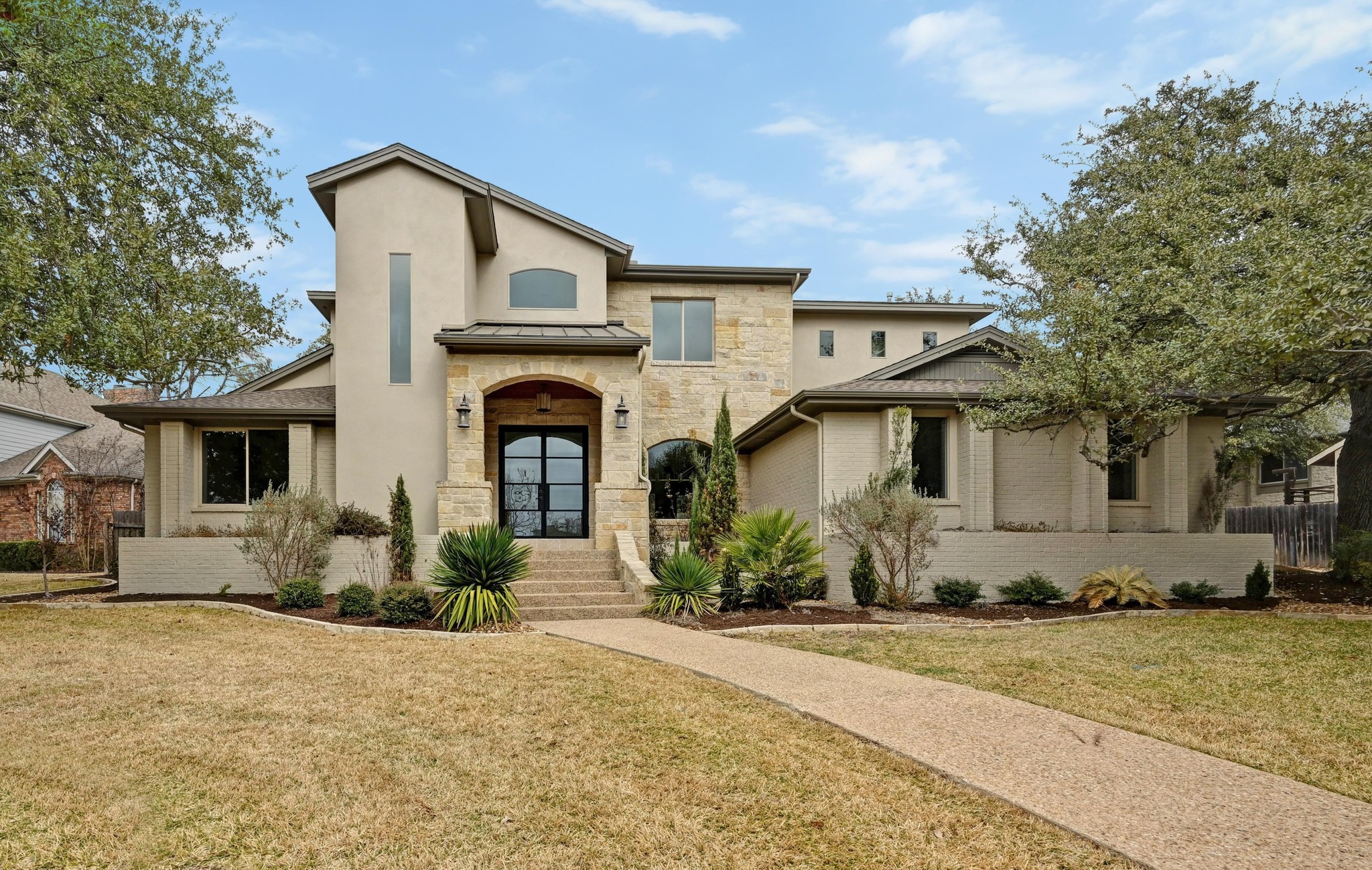 View of front of home featuring a front yard, stone siding, and a standing seam roof