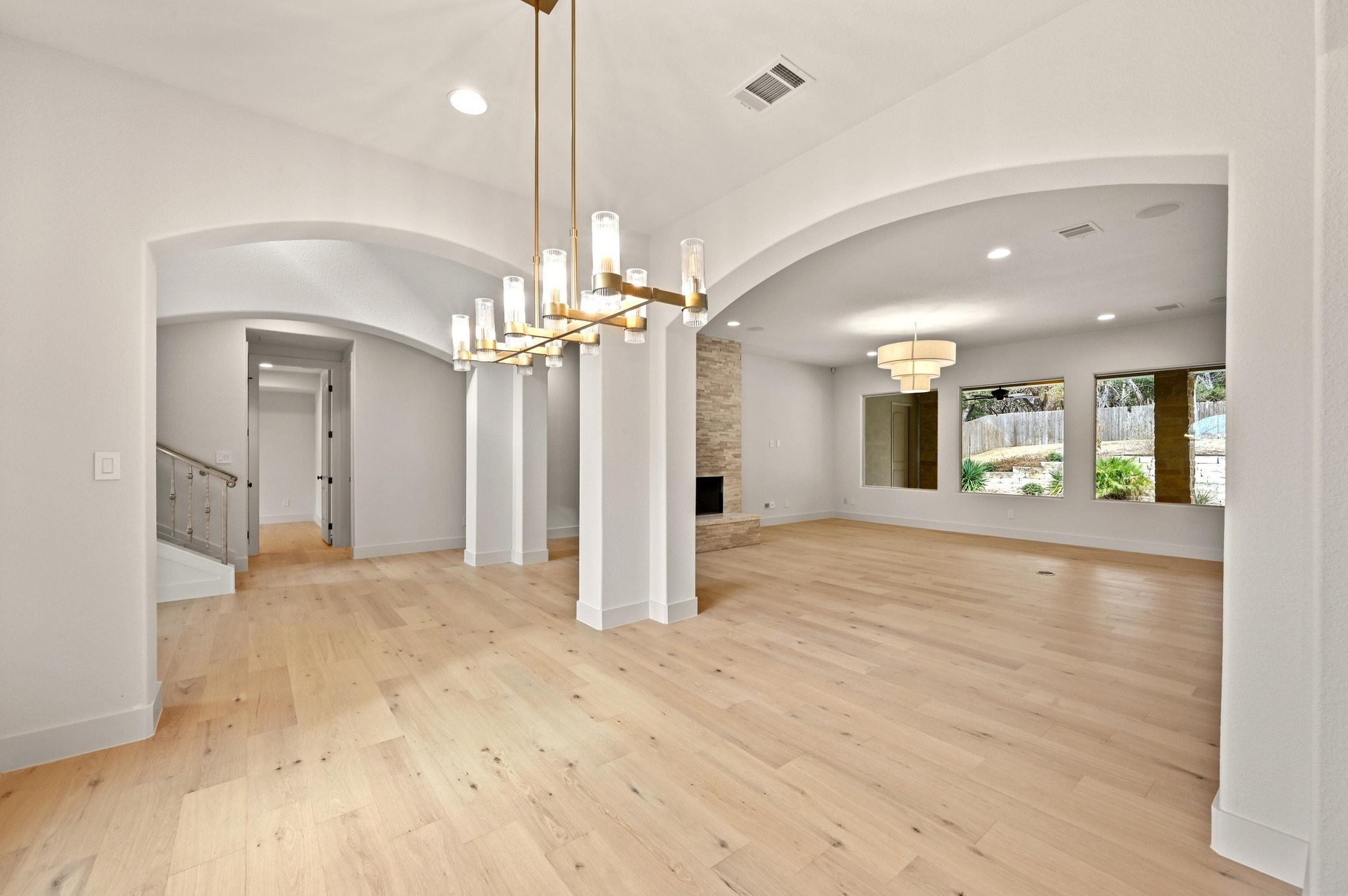 2800 Barton Point Drive Austin, TX 78733 - Photo 4 of 40 Unfurnished dining area with hanging lights, arched walkways, light wood-type flooring, and a stone fireplace