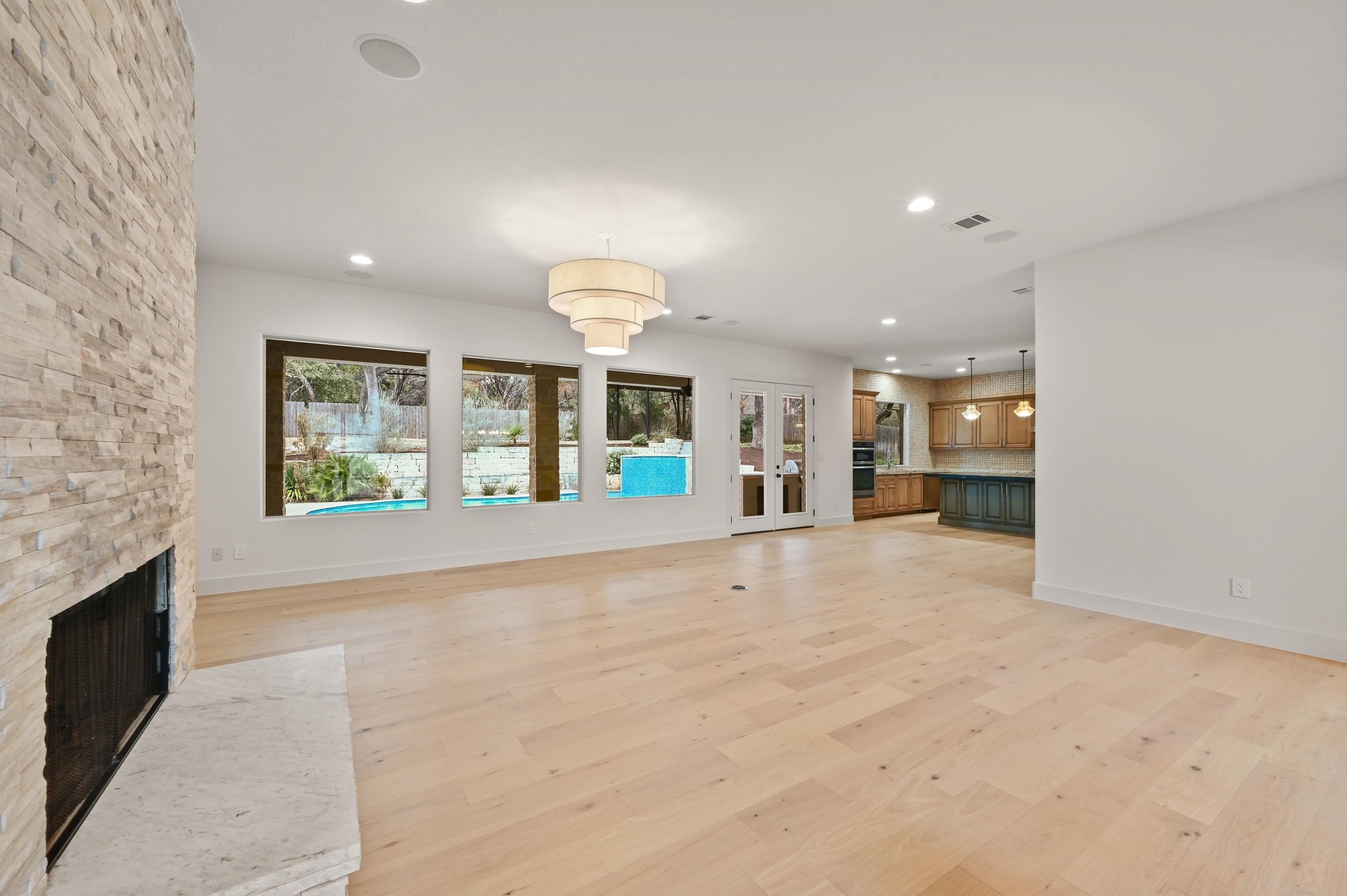 2800 Barton Point Drive Austin, TX 78733 - Photo 5 of 40 Unfurnished living room featuring a stone fireplace, light wood-style flooring, and recessed lighting