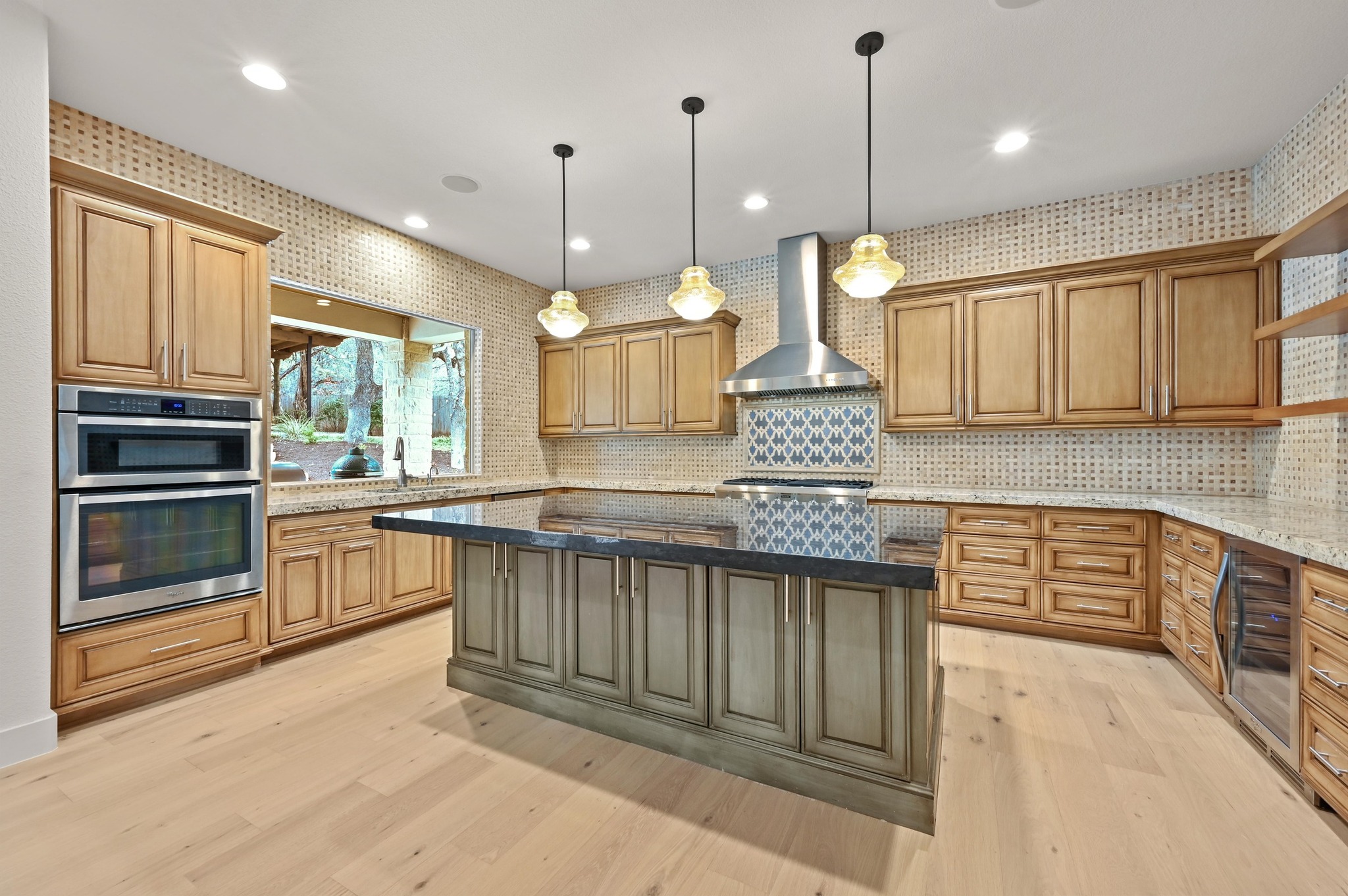 2800 Barton Point Drive Austin, TX 78733 - Photo 9 of 40 Kitchen with dark stone countertops, decorative light fixtures, a center island, light wood finished floors, and dual tone cabinetry