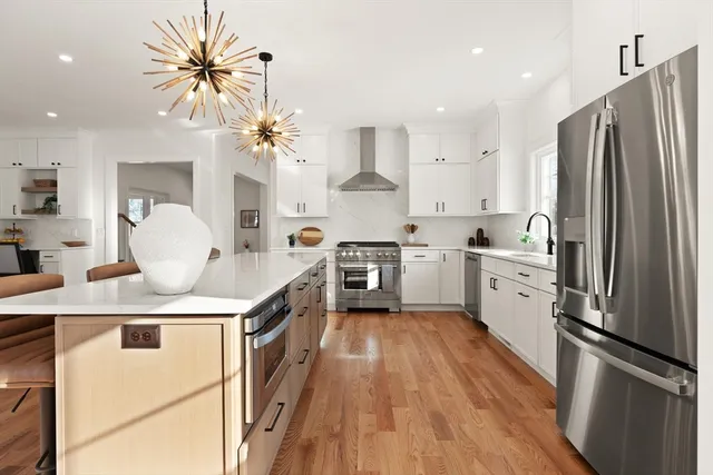 a kitchen with stainless steel appliances a sink a stove a refrigerator a center island and cabinets