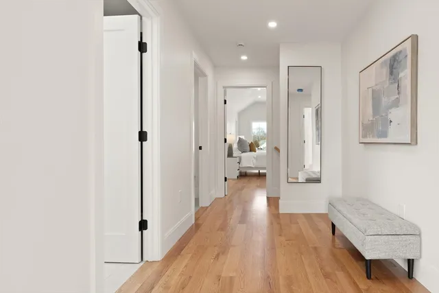 a view of a hallway with wooden floor and a bathroom