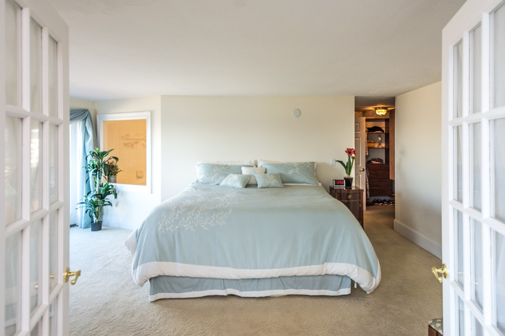 63 Oceanside Drive, Unit 63 Hull, MA 02045 - Photo 19 of 30 a spacious bedroom with a bed and a potted plant