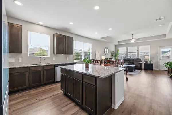 a kitchen with stainless steel appliances granite countertop a stove a sink a microwave a refrigerator and chairs