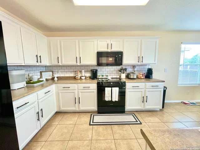 a kitchen with white cabinets appliances and a window