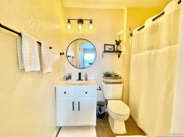 a bathroom with a toilet sink vanity and mirror