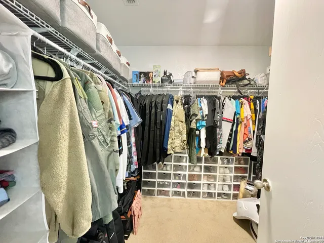 a view of walk in closet with clothes and shoes