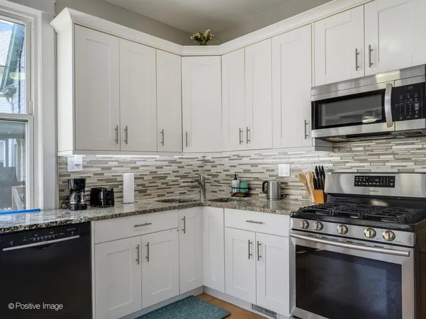 a kitchen with stainless steel appliances granite countertop grey cabinets a stove a sink and dishwasher
