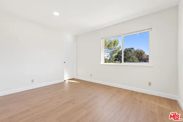 an empty room with wooden floor and window