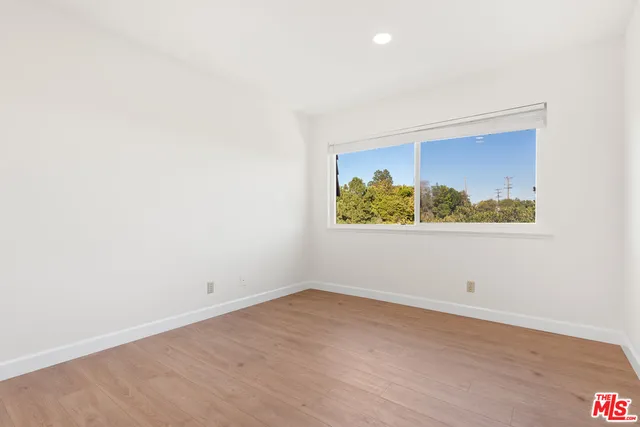 an empty room with wooden floor and window