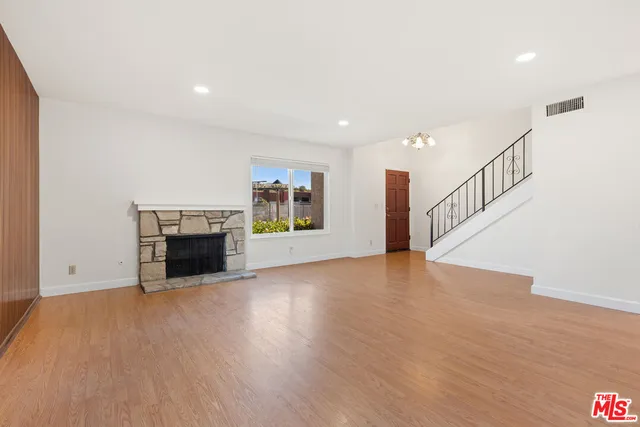 a view of empty room with wooden floor and fireplace