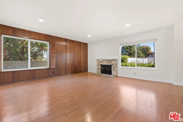 an empty room with windows fire place and front door