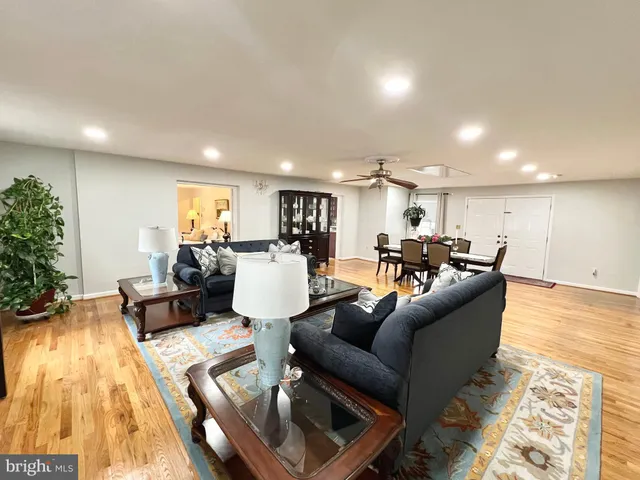 a living room with furniture and a dining table with wooden floor