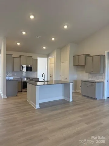 a large kitchen with stainless steel appliances granite countertop a large counter top a sink and cabinets