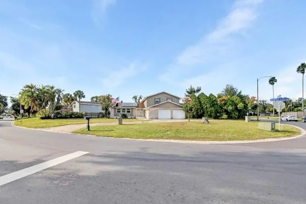 a view of a house with a yard and a large tree