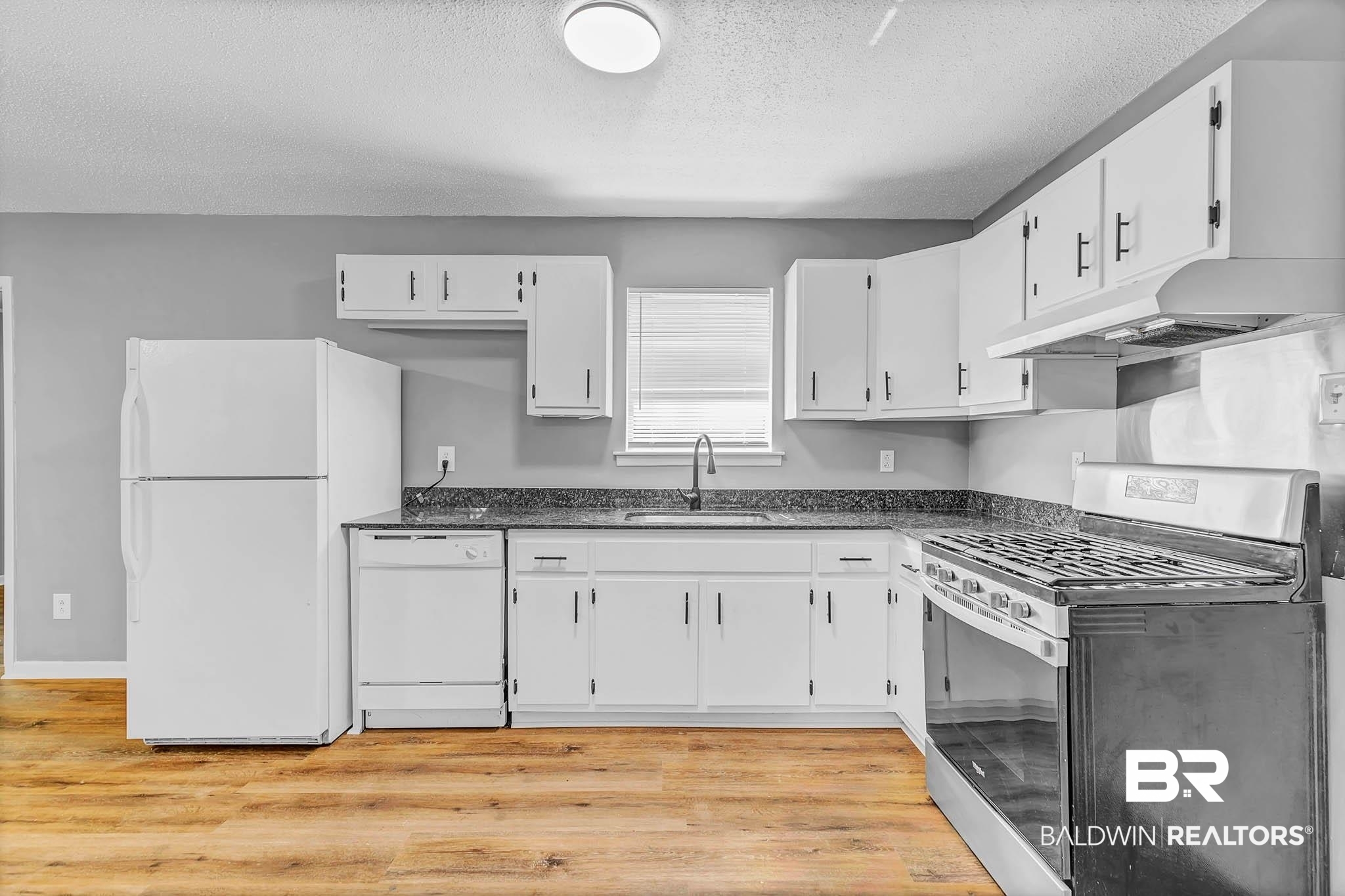 3304 Armond Drive Mobile, AL 36605 - Photo 17 of 62 Kitchen featuring white appliances, a textured ceiling, under cabinet range hood, white cabinets, and light wood-style flooring