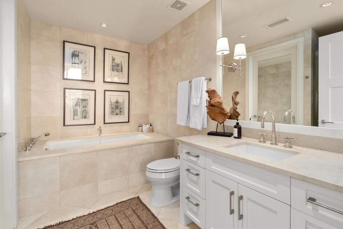98 San Jacinto Boulevard, Unit 1201 Austin, TX 78701 - Photo 12 of 22 a bathroom with a double vanity sink toilet mirror and bathtub