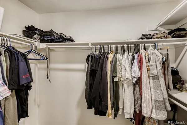 a view of walk in closet with clothes and shoes