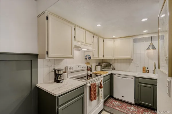 a kitchen with a sink a stove a refrigerator and white cabinets
