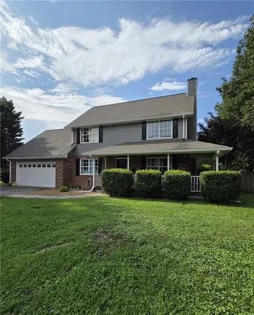 a view of a house next to a big yard and large trees