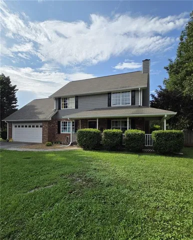 a view of a house next to a big yard and large trees