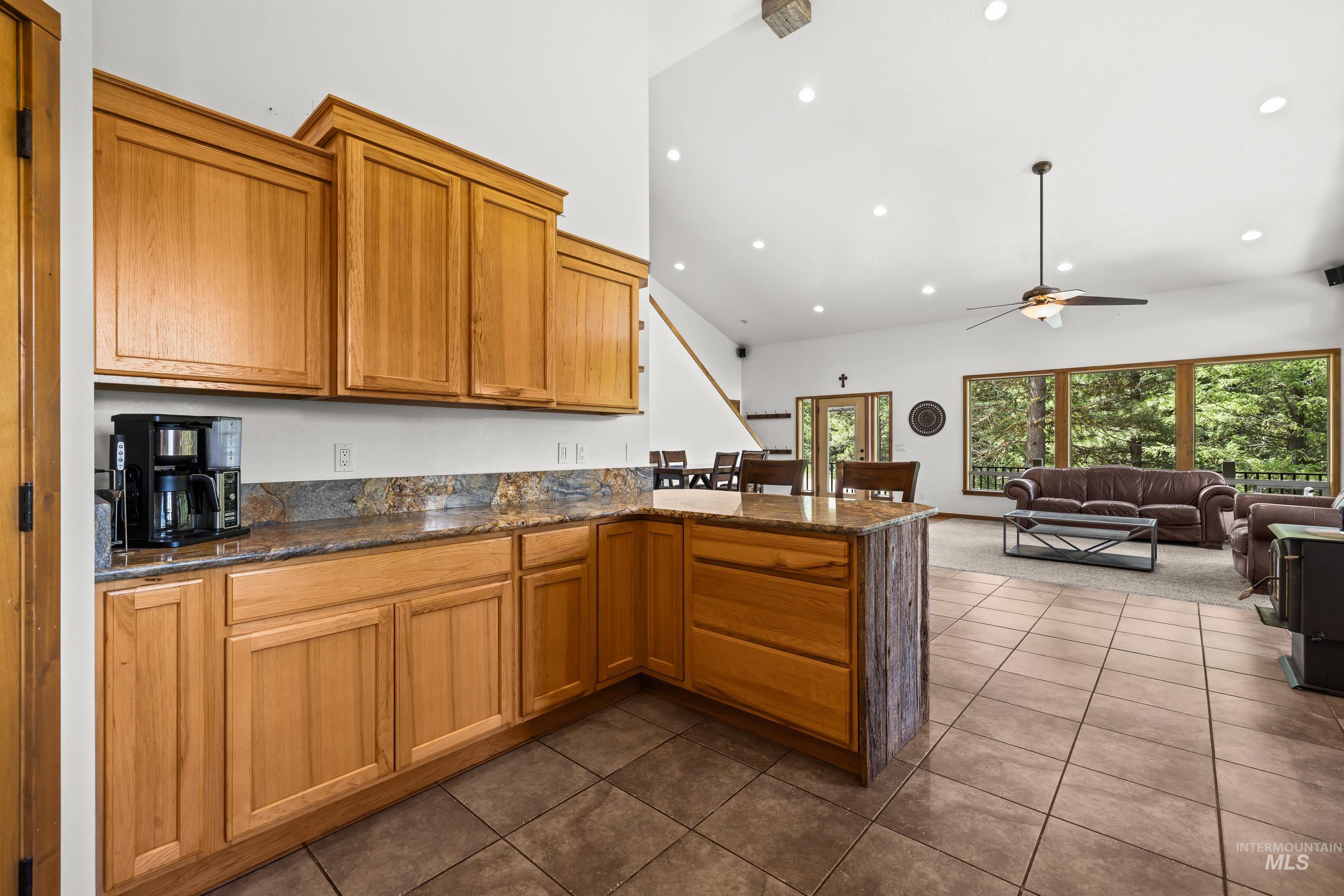 92 Cruickshank Road Horseshoe Bend, ID 83629 - Photo 19 of 50 Open-concept kitchen featuring wood cabinetry, stone countertops, and a tile backsplash
