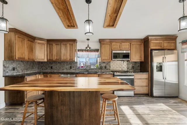 a kitchen with kitchen island stainless steel appliances a sink stove and wooden floor