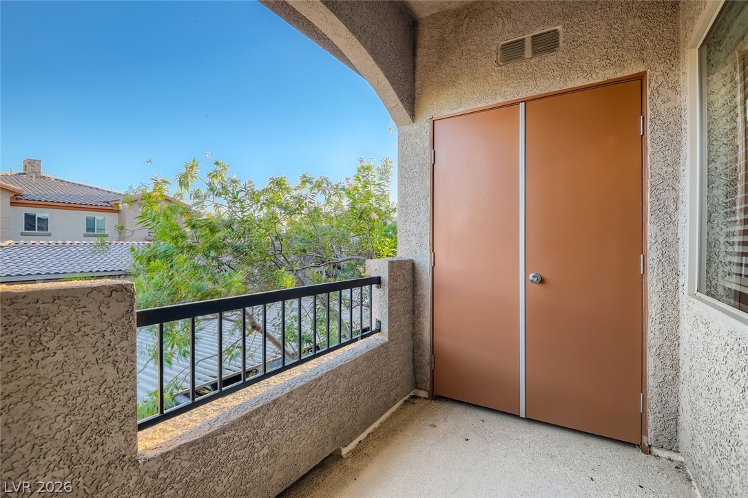 7701 West Robindale Road, Unit 265 Las Vegas, NV 89113 - Photo 25 of 27 An arched covered balcony offers textured stucco walls and views of the surrounding neighborhood greenery.