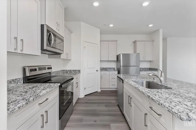 a kitchen with stainless steel appliances granite countertop a sink stove and refrigerator