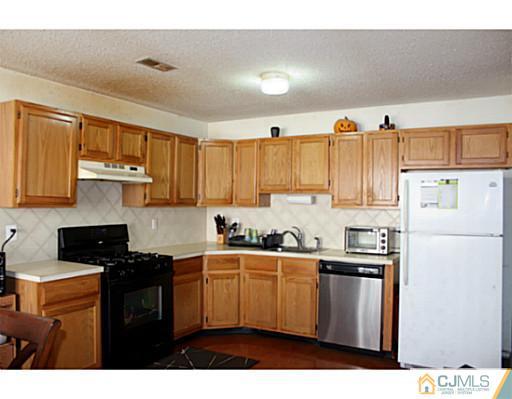2 Inverness Drive Edison, NJ 08820 - Photo 3 of 14 a kitchen with stainless steel appliances a sink a stove a refrigerator cabinets and a window