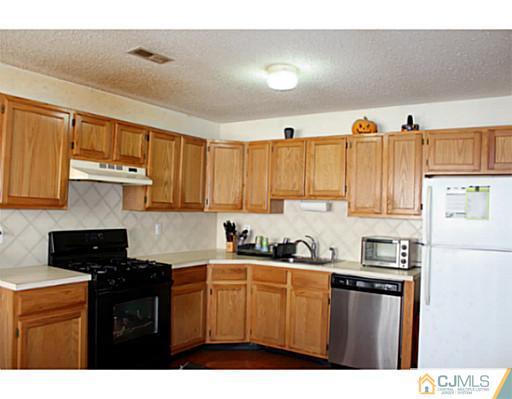 2 Inverness Drive Edison, NJ 08820 - Photo 10 of 14 a kitchen with stainless steel appliances a sink a stove a refrigerator cabinets and a window