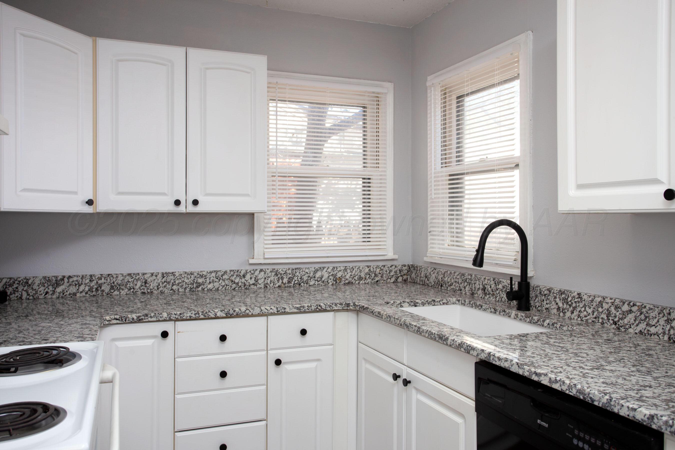 4215 South Travis Street Amarillo, TX 79110 - Photo 2 of 20 a kitchen with granite countertop white cabinets and a sink