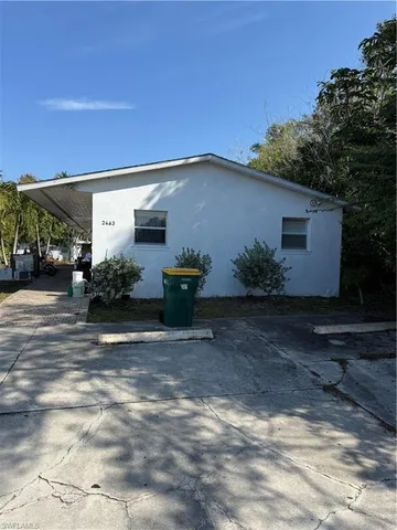 a backyard of a house with potted plants and large trees