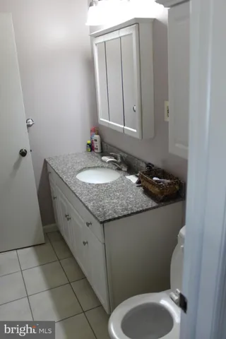 a bathroom with a granite countertop toilet and a sink