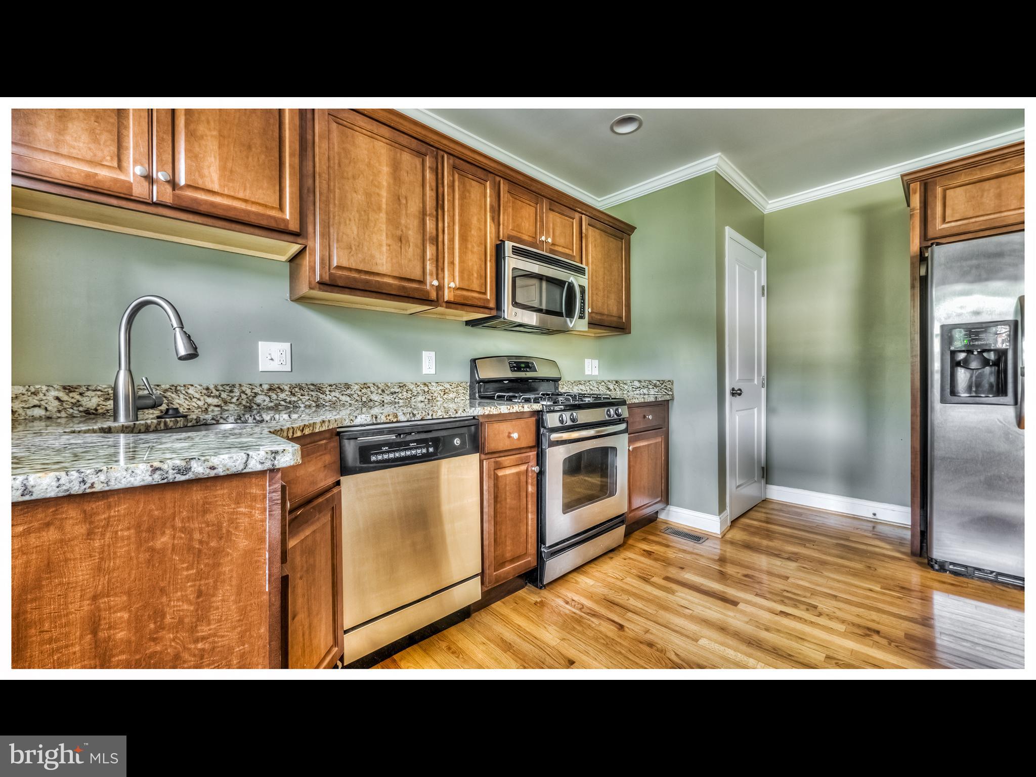 836 Bradhurst Road Baltimore, MD 21212 - Photo 3 of 24 a open kitchen with stainless steel appliances granite countertop a stove a sink and a microwave