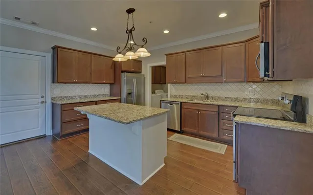a kitchen with kitchen island granite countertop a sink cabinets and wooden floor
