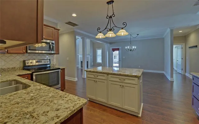 a kitchen with stainless steel appliances granite countertop a sink a stove and a wooden floors