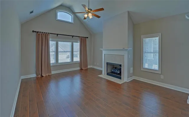 an empty room with wooden floor fireplace and windows
