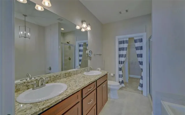 a bathroom with a granite countertop sink a toilet a mirror and shower