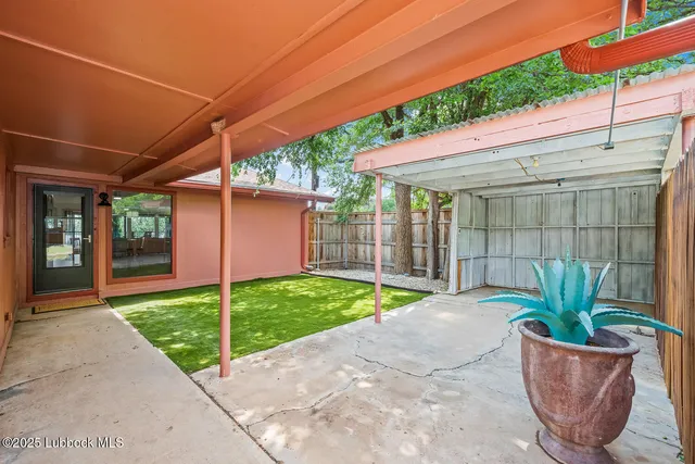 a backyard of a house with plants and trees with wooden fence