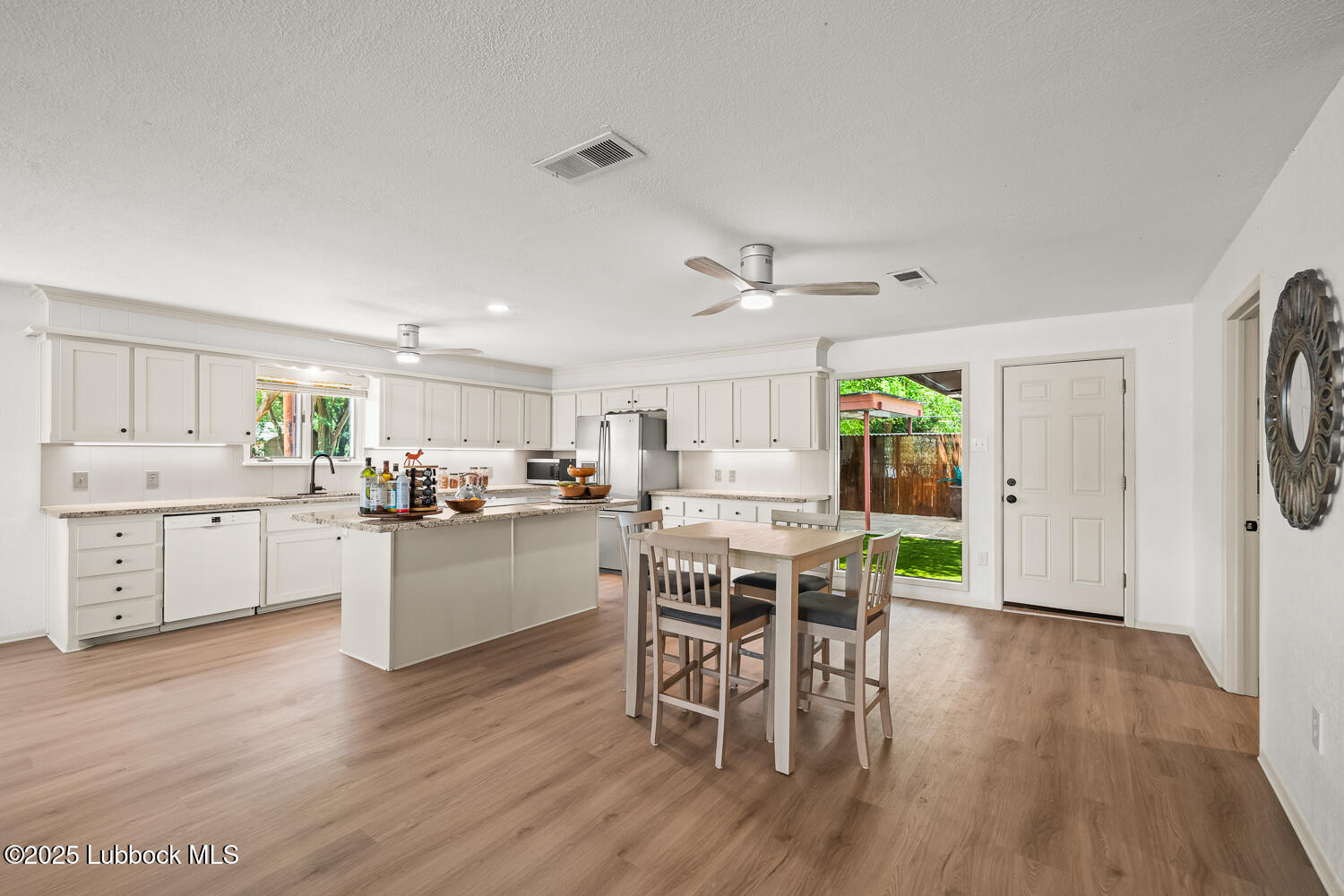 146 Pony Express Trail Buffalo Springs, TX 79404 - Photo 8 of 48 a kitchen with a dining table chairs wooden floor cabinets and stainless steel appliances