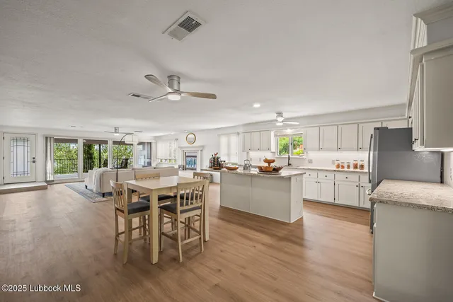 a kitchen with a dining table chairs wooden floor cabinets and stainless steel appliances