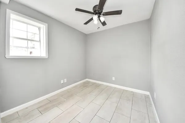 an empty room with windows and fan