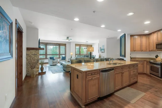 a kitchen with stainless steel appliances granite countertop a dining table chairs refrigerator sink and cabinets
