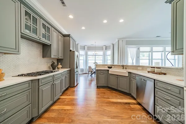 a large kitchen with stainless steel appliances granite countertop lots of counter top space and wooden floor