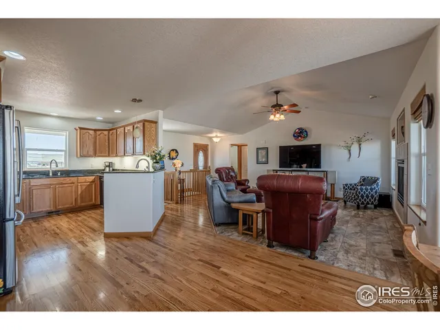 a living room with furniture a wooden floor and a kitchen