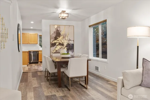 a kitchen with stainless steel appliances granite countertop a sink a stove a refrigerator cabinets and a dining table