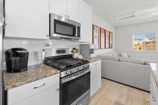 a kitchen with stainless steel appliances granite countertop a stove a sink and a microwave