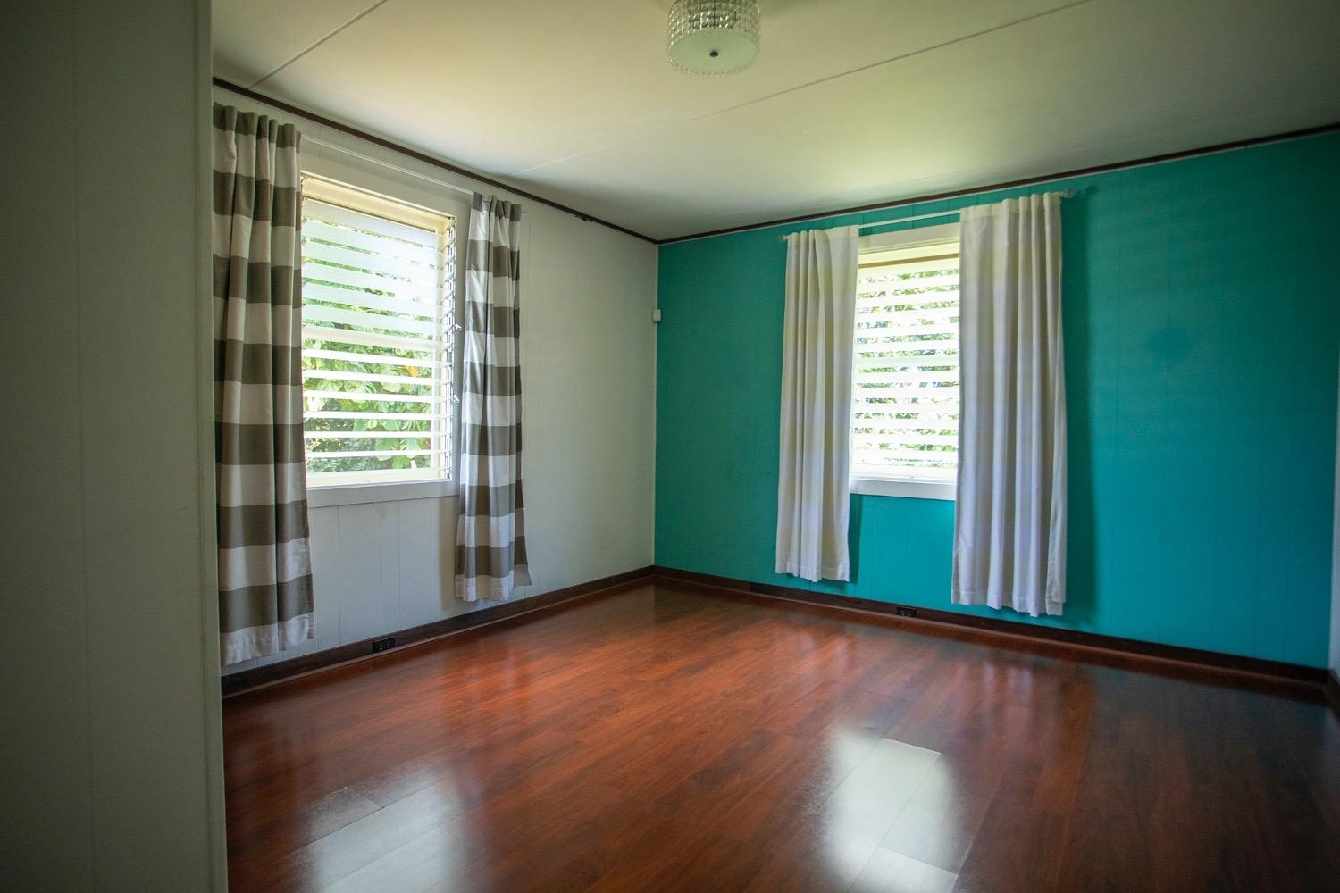 741 Haiku Road Haiku, HI 96708 - Photo 15 of 26 an empty room with wooden floor and windows with curtains