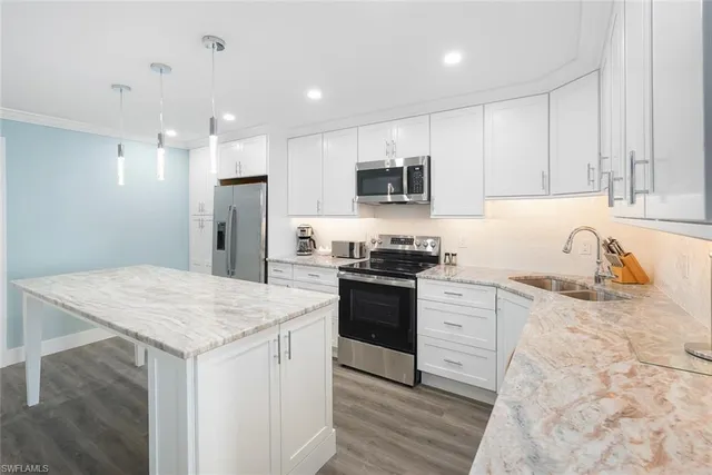 a kitchen with granite countertop a sink stove and refrigerator
